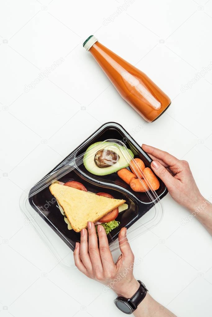 cropped image of woman opening plastic lunch box with food isolated on white