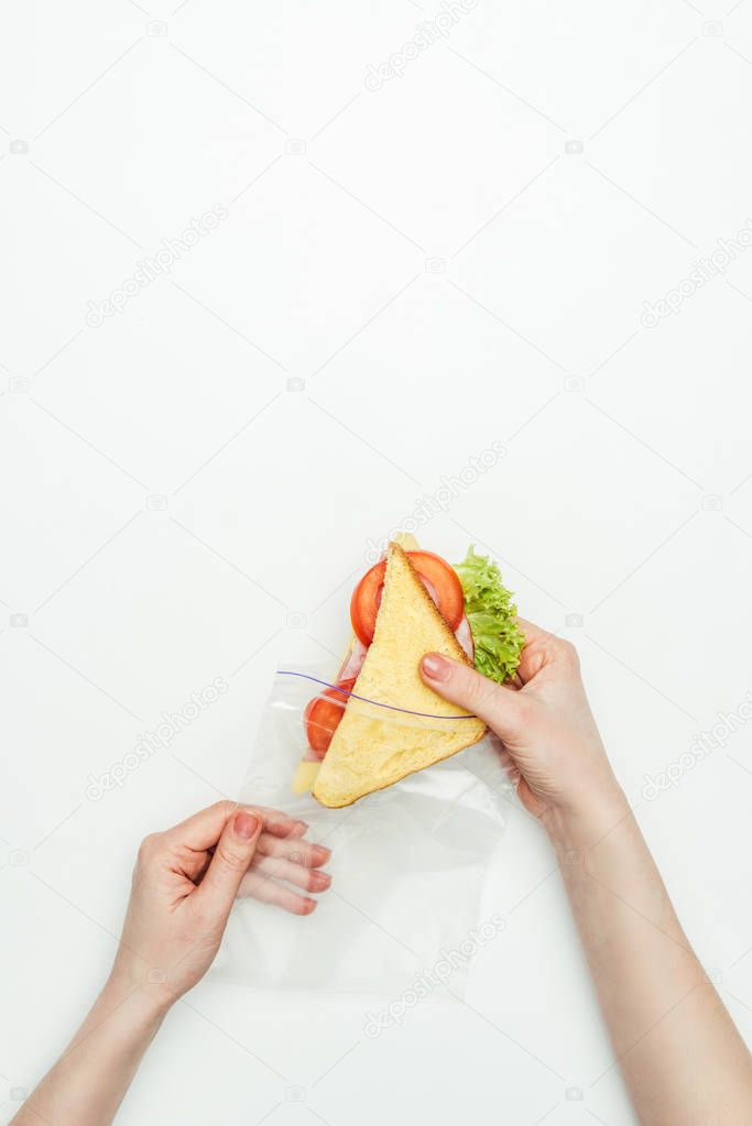 cropped image of woman packing sandwich in plastic ziplock bag isolated on white