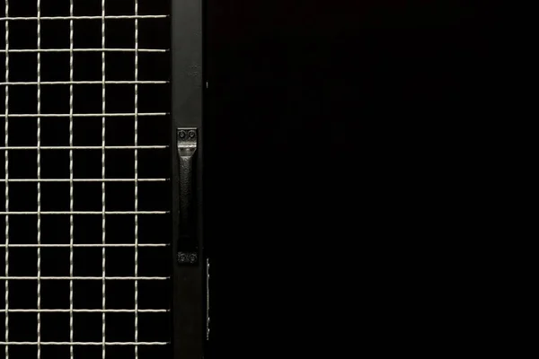 Black door with handle and metal grit on black background