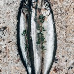 Three salted fish with rosemary on rustic surface