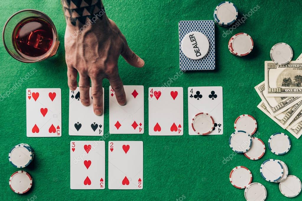 Man choosing cards by whiskey on casino table