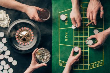 People drinking alcohol while playing roulette by casino table clipart