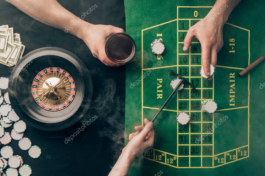 Smoke over people placing bets while playing roulette on casino table