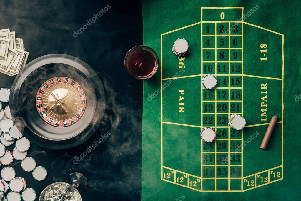 Casino table with roulette and glass with whiskey