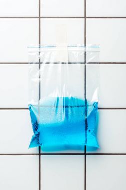 ziplock plastic bag with blue water hanging on tile wall, earth day concept clipart