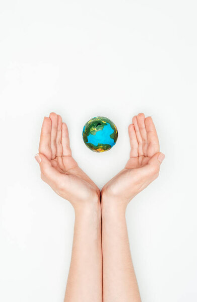 cropped image of woman holding hands around earth model isolated on white, earth day concept