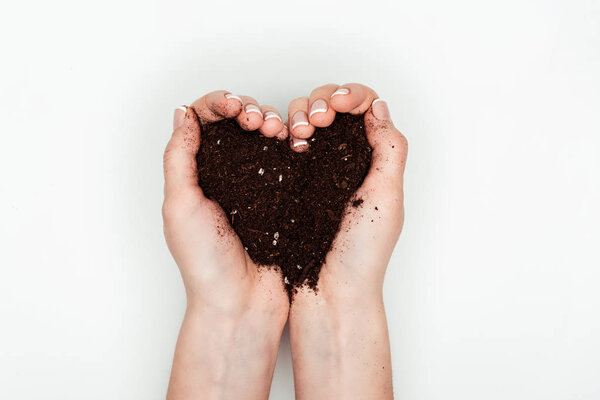 cropped image of woman holding heart shaped soil in hands isolated on white, earth day concept