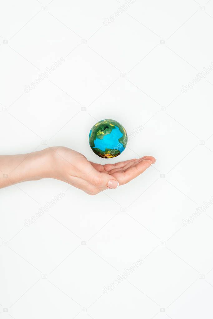cropped image of woman holding hand near earth model isolated on white, earth day concept