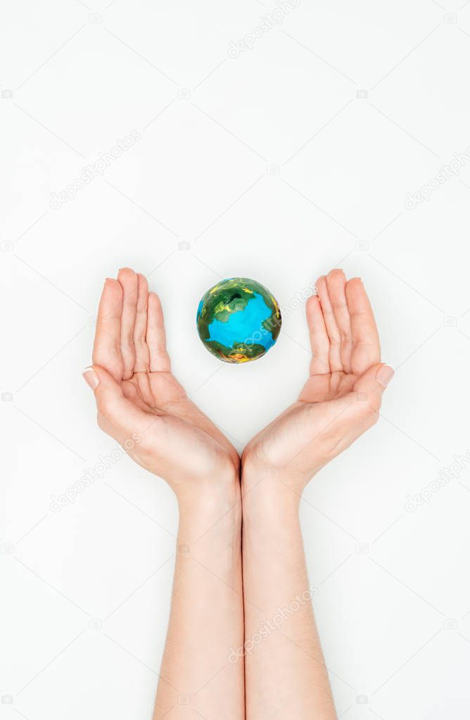 cropped image of woman holding hands around earth model isolated on white, earth day concept