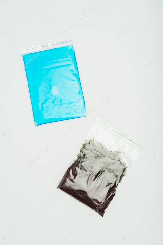 top view of ziplock bags with blue water and soil isolated on white, earth day concept