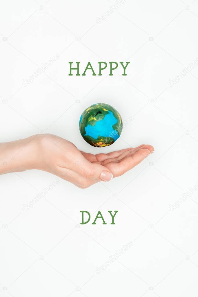 cropped image of woman holding earth model on hand with sign happy earth day isolated on white