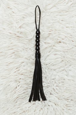 Black strict leather flogging whip on white carpet clipart