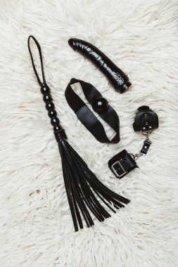 Black bdsm gag and vibrator with whip on white carpet clipart
