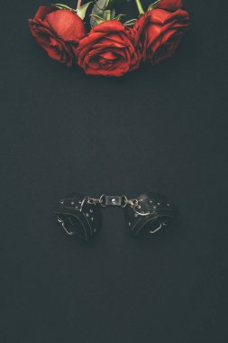 Leather handcuffs with rose flowers isolated on black clipart