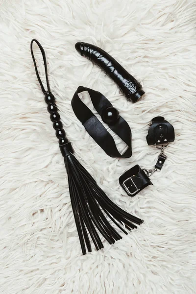 白色地毯上有鞭子的黑色 Bdsm 和振动器 — 图库照片
