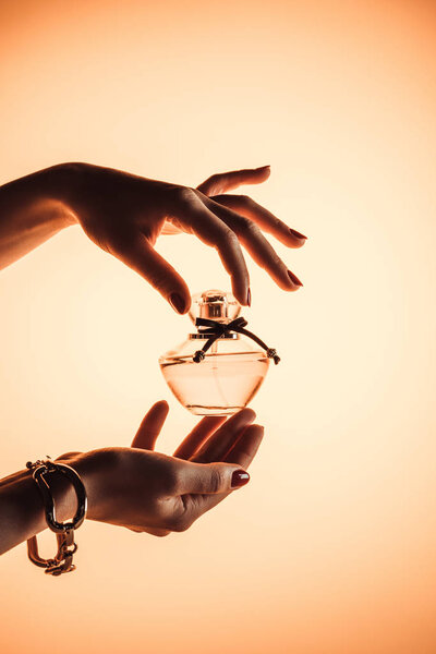 cropped view of woman holding sensual perfume, isolated on yellow