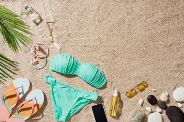 Mavi bikini çeşitli aksesuarlar ile üstten görünüm kum plajındaki
