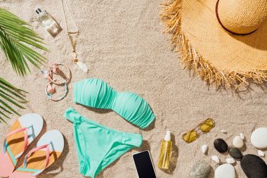 kum plajındaki mavi bikini ve çeşitli aksesuarlar ile flip flop Üstten Görünüm