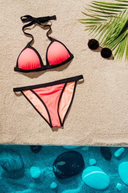 top view of stylish pink bikini with sunglasses on sandy beach clipart
