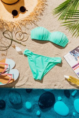 şık mavi bikini çeşitli aksesuar ve dergi ile üstten görünüm kum plajındaki
