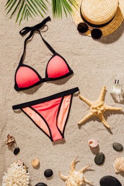 Aksesuar ve parfüm pembe bikini üst görünümden kum plajındaki