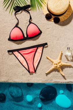 Aksesuar ve parfüm şık pembe bikini üst görünümden kum plajındaki