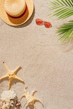 top view of straw hat with sunglasses on sandy beach
