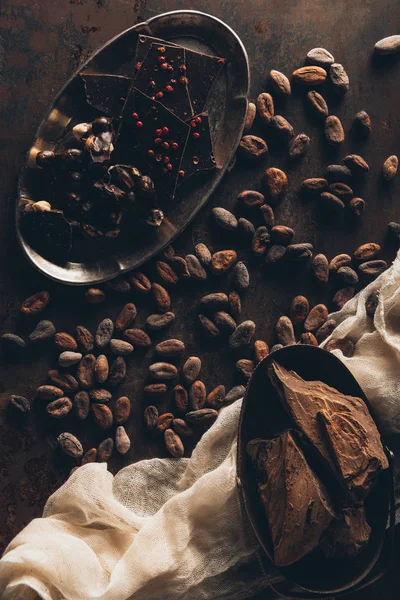 Stock image top view of delicious chocolate pieces, nuts and cocoa beans on dark surface