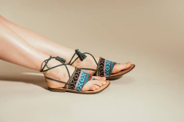 kadın ayak bej renkli arka plan üzerinde şık Sandaletler içinde kırpılmış görüntü