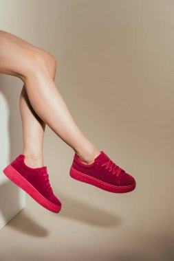kadın bacak bej renkli arka plan üzerinde şık spor ayakkabı içinde kırpılmış görüntü