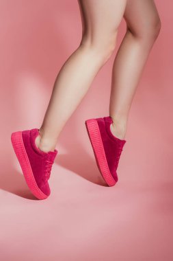 kızın ayak pembe bir arka plan üzerinde duran şık spor ayakkabı içinde kırpılmış görüntü