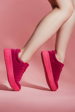 cropped shot of girl in stylish sneakers standing on toes on pink background clipart