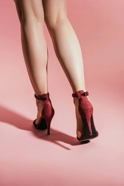 女性腿的后方看法在时尚高跟鞋在粉红色背景 — 图库照片