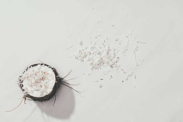 top view of half of coconut and shavings on white