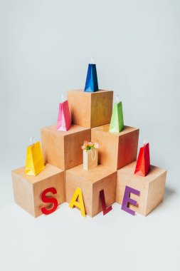 high angle view of colored shopping bags on wooden stands with sale sign, summer sale concept clipart