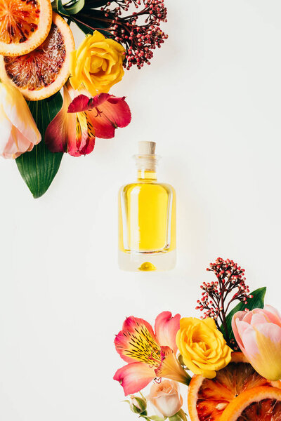 top view of bottle of aromatic perfume with beautiful flowers and grapefruit slices isolated on white