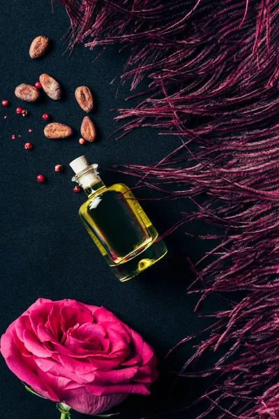 红色羽毛和玫瑰色芽的香水瓶的顶部看法在黑 — 图库照片