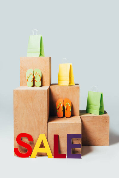 colored shopping bags on wooden stands with sale sign, summer sale concept