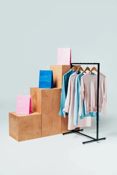 wooden stands with paper bags and stand with clothes on white, summer sale concept