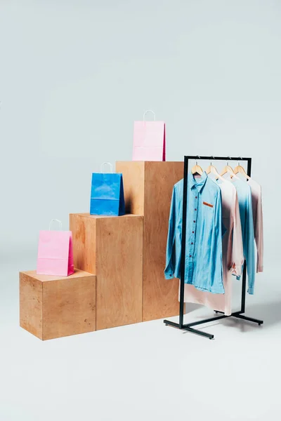 wooden stands with shopping bags and stand with clothes on white, summer sale concept