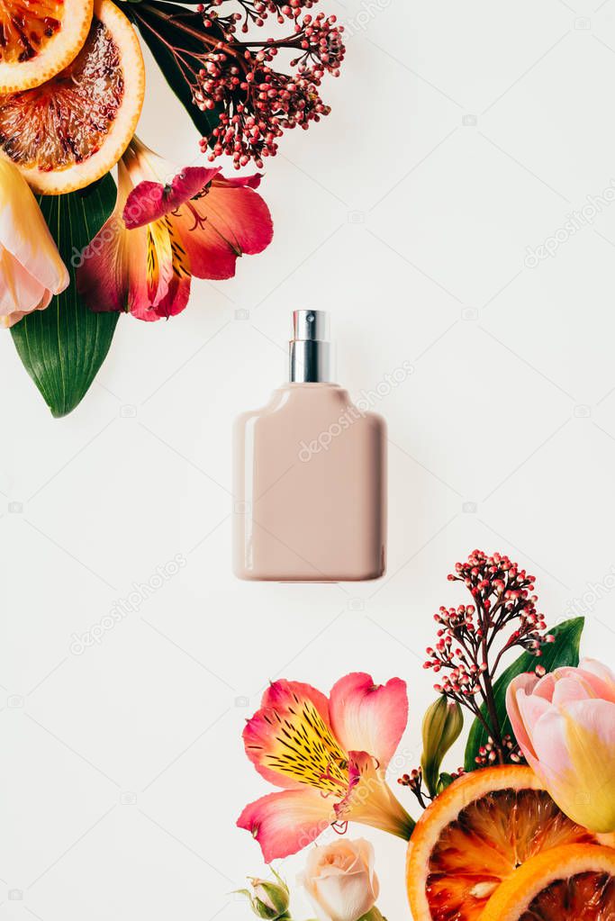 top view of bottle of aromatic perfume with various flowers and grapefruit slices isolated on white