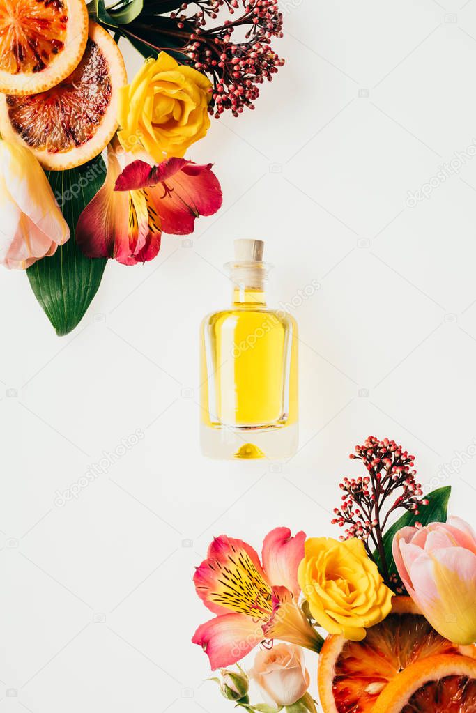 top view of bottle of aromatic perfume with beautiful flowers and grapefruit slices isolated on white
