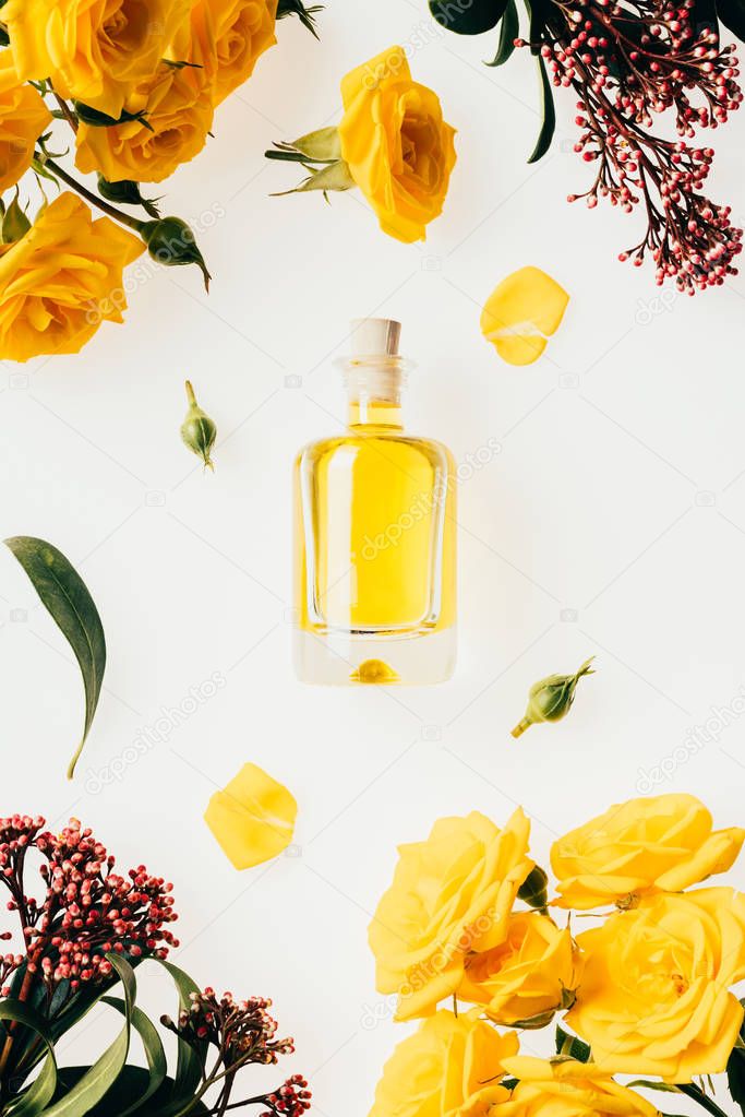 top view of bottle of perfume with aromatic flowers around isolated on white