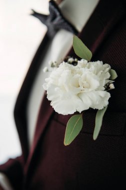 partial view of groom in suit with beautiful white corsage clipart