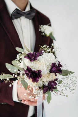 partial view of groom in suit with beautiful wedding bouquet in hands clipart