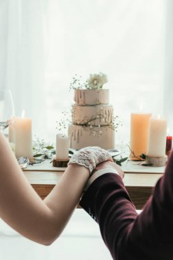 Düğün pastası, rustik düğün konsepti ile hizmet masada otururken el ele tutuşarak yeni evliler kısmi görünümünü