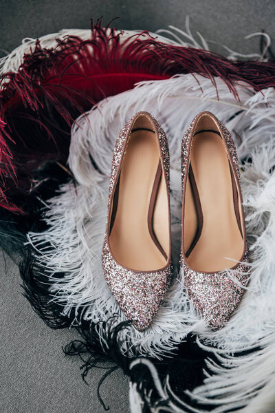 close up view of bridal shoes and decorative feathers for rustic wedding on armchair