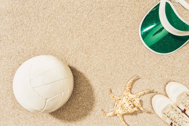 düz lay voleybol topu, kap, spor ayakkabı ve kum deniz yıldızı ile