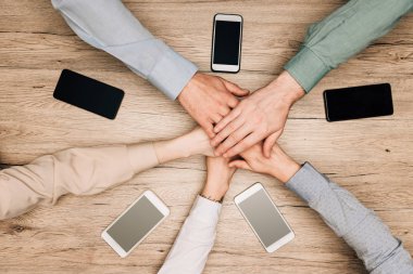 İş ortaklarının masadaki akıllı telefonlardan el ele tutuşmaları, kırpılmış görüntüler