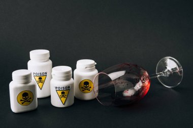 Zehirli işaretli şişeler ve siyah üzerinde kan olan şarap kadehleri.